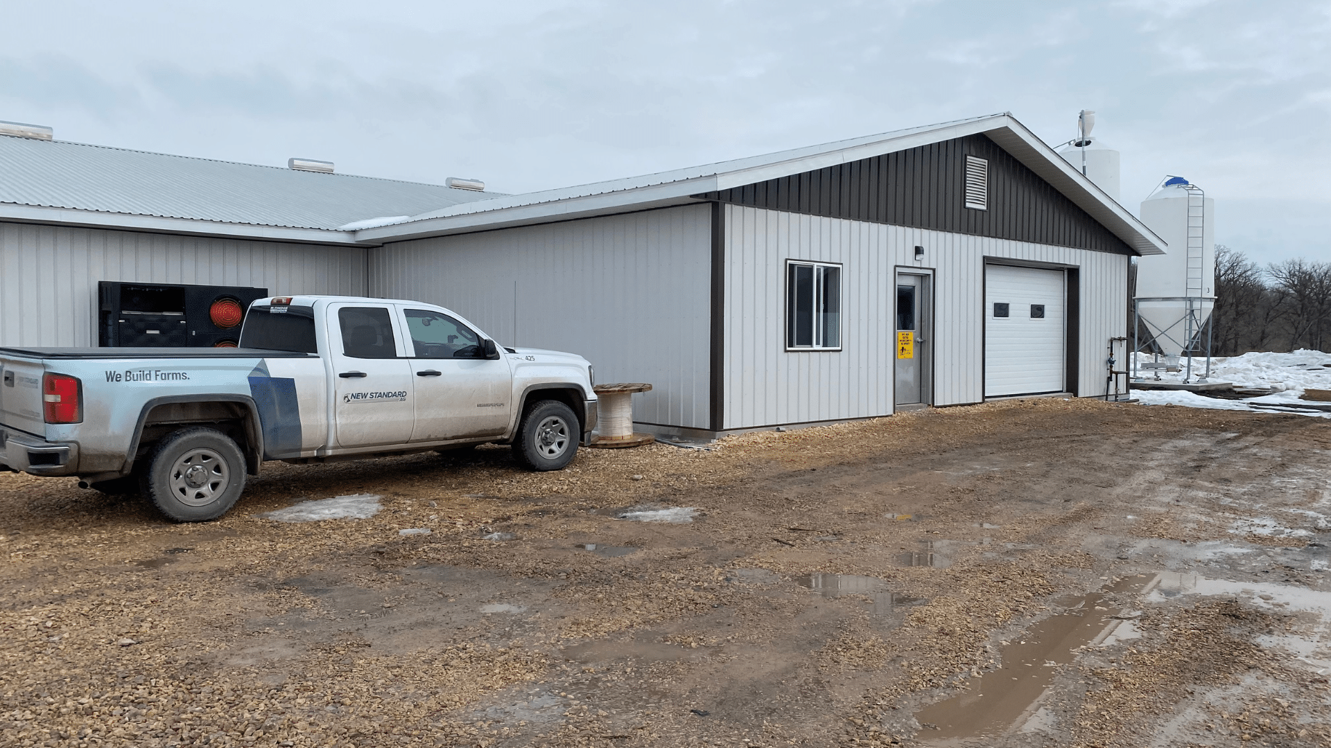 A truck with a new standard logo parked outside a farm office in winter.