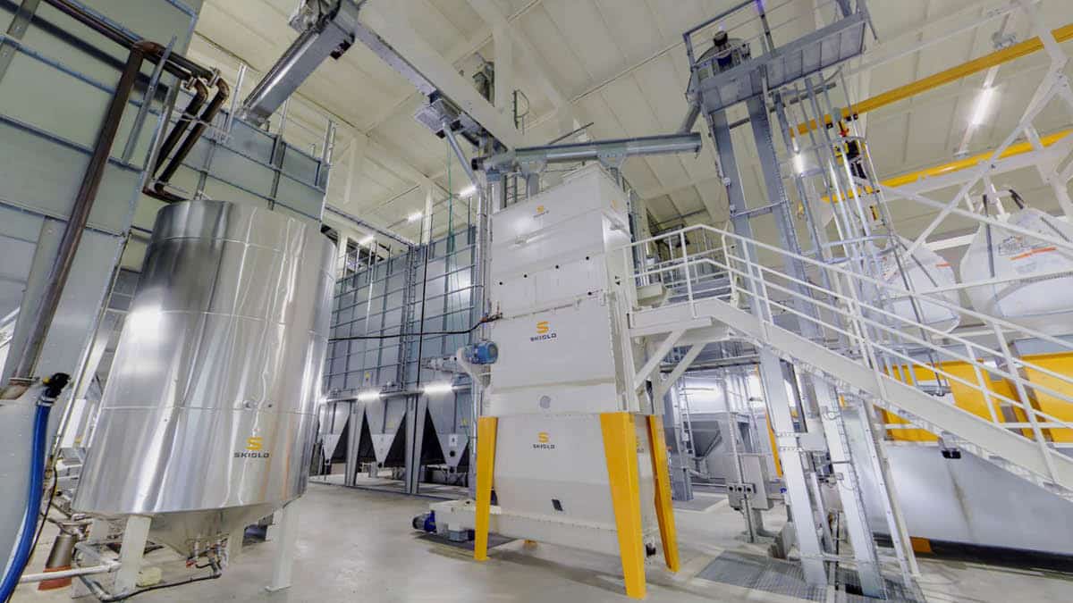 Modern agricultural processing facility showcasing advanced feed production equipment, including stainless steel silos and automated conveyor systems. The machinery is designed for efficiency and precision in feed manufacturing. The structure represents innovative solutions for the agribusiness sector